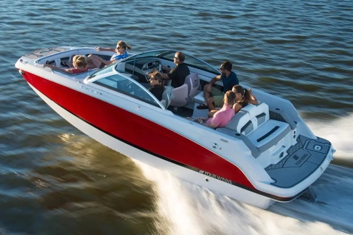 People enjoying a ride on a red and white speedboat on the water.
