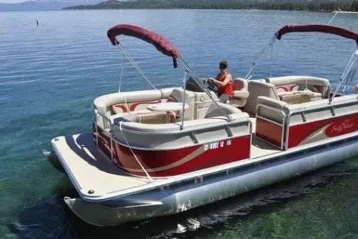 Pontoon boat with red canopy on clear blue lake water.